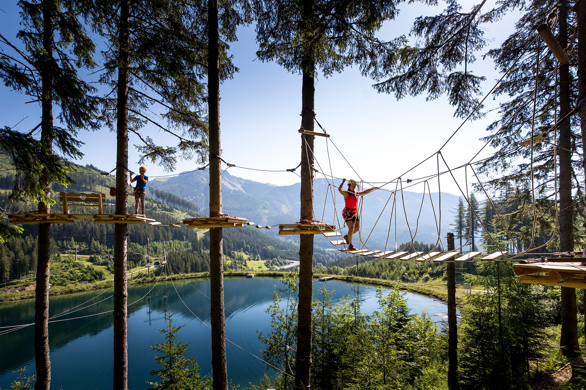 Personen im ADVENTUREPARK-Hochseilgarten mit Seepanorama, Link zu Alpfox.