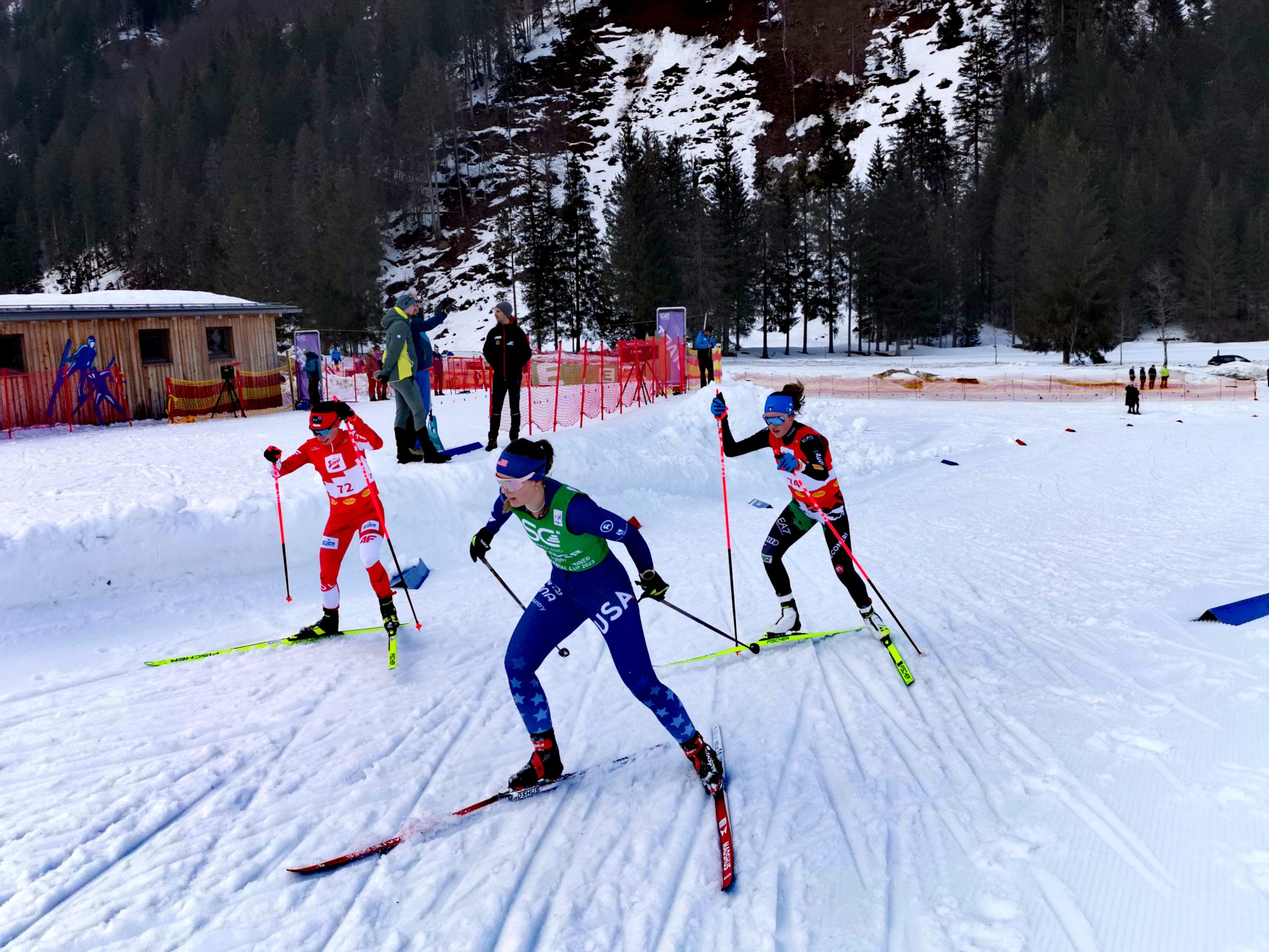 Drei Damen beim Langlaufen während des Continental Cups in der Erzberg Arena, mit der Strecke und Bäumen im Hintergrund.